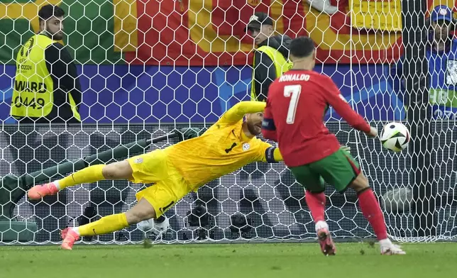 Slovenia's goalkeeper Jan Oblak blocks a penalty kick by Portugal's Cristiano Ronaldo (7) during a round of sixteen match at the Euro 2024 soccer tournament in Frankfurt, Germany, Monday, July 1, 2024. (AP Photo/Ebrahim Noroozi)