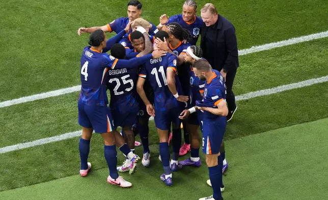 Cody Gakpo of the Netherlands, center, celebrates with teammates and head coach Ronald Koeman after scoring the opening goal during a round of sixteen match between Romania and the Netherlands at the Euro 2024 soccer tournament in Munich, Germany, Tuesday, July 2, 2024. (AP Photo/Frank Augstein)