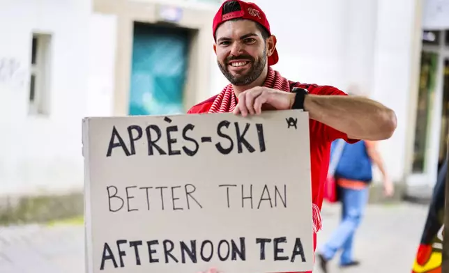 A Swiss fan shows a sign reading "Apres-Ski better than Afternoon Tea" ahead of the Euro 2024 quarterfinal soccer match between Switzerland and England in Dusseldorf, Germany, Saturday, July 6, 2024. (Christoph Reichwein/dpa via AP)