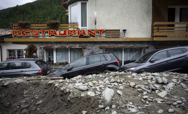 Cars stuck in the rubble from a landslide caused by severe weather following storms that caused major flooding and landslide are pictured in Saas-Grund, Switzerland, Sunday, June 30, 2024. Authorities say weekend storms in Switzerland and northern Italy caused extensive flooding and landslides, leaving at least four people dead. Storms and heavy rain affected southern and western Switzerland on Saturday and overnight. (Olivier Maire/Keystone via AP)