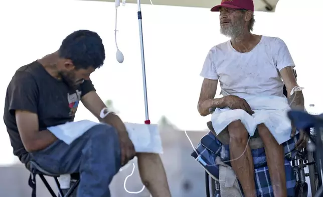 Phillip Enriquez, left, and Alfred Handley receive intravenous saline solution from a Circle The City mobile clinic, Thursday, May 30, 2024 in Phoenix. Based in the hottest big metro in America, Circle the City is taking measures to protect patients from life-threatening heat illness as temperatures hit new highs. Homeless people accounted for nearly half of the record 645 heat-related deaths last year in Arizona's Maricopa County, which encompasses metro Phoenix.(AP Photo/Matt York)