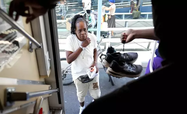 A homeless woman is given a pair of shoes from a nurse working aboard one of five Circle The City mobile clinics stationed outside soup kitchens and other services for homeless people, Thursday, May 30, 2024 in Phoenix. Based in the hottest big metro in America, Circle the City is taking measures to protect patients from life-threatening heat illness as temperatures hit new highs. Homeless people accounted for nearly half of the record 645 heat-related deaths last year in Arizona's Maricopa County, which encompasses metro Phoenix.(AP Photo/Matt York)