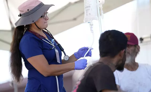 Nurse practitioner Perla Puebla prepares a intravenous saline solution outside a Circle The City mobile clinic, Thursday, May 30, 2024 in Phoenix. Based in the hottest big metro in America, Circle the City is taking measures to protect patients from life-threatening heat illness as temperatures hit new highs. Homeless people accounted for nearly half of the record 645 heat-related deaths last year in Arizona's Maricopa County, which encompasses metro Phoenix.(AP Photo/Matt York)