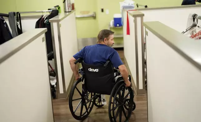 Ron Falk, 62, uses his wheelchair to navigate the corridors of his temporary lodging, Tuesday, June 25, 2024 in Phoenix. Falk lost his right leg, had extensive skin grafting on the left one and is still recovering a year after collapsing on the searing asphalt outside a convenience store where he stopped for a cold soda during a blistering heat wave. (AP Photo/Matt York)