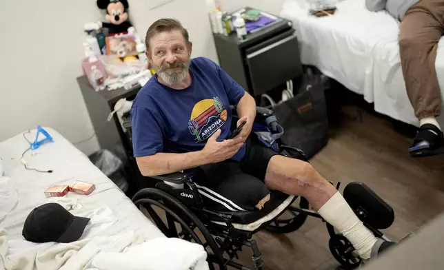 Ron Falk, 62, speaks of losing his leg, Tuesday, June 25, 2024 in Phoenix. Falk lost his right leg, had extensive skin grafting on the left one and is still recovering a year after collapsing on the searing asphalt outside a convenience store where he stopped for a cold soda during a blistering heat wave. (AP Photo/Matt York)