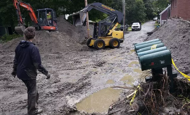 An excavator and loader clear Hudson Avenue of mud after remnants of Hurricane Beryl caused flooding and destruction, Friday, July 12, 2024, in Plainfield, Vt. (AP Photo/Charles Krupa)