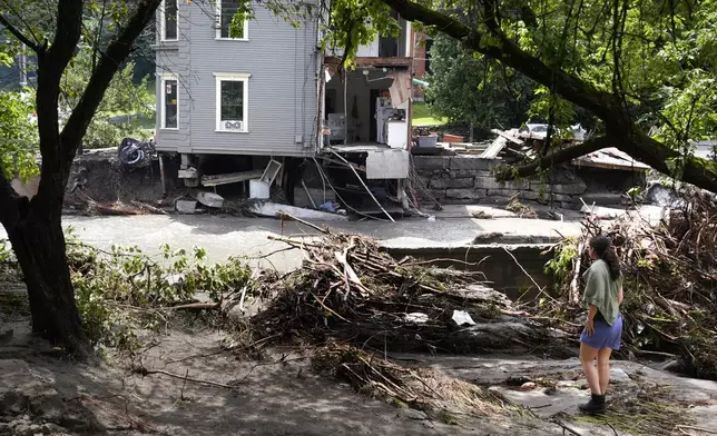 A woman looks at what remains of an apartment building, of which about one third of the building broke away and was carried downstream, after remnants of Hurricane Beryl caused flooding and destruction, Friday, July 12, 2024, in Plainfield. (AP Photo/Charles Krupa)