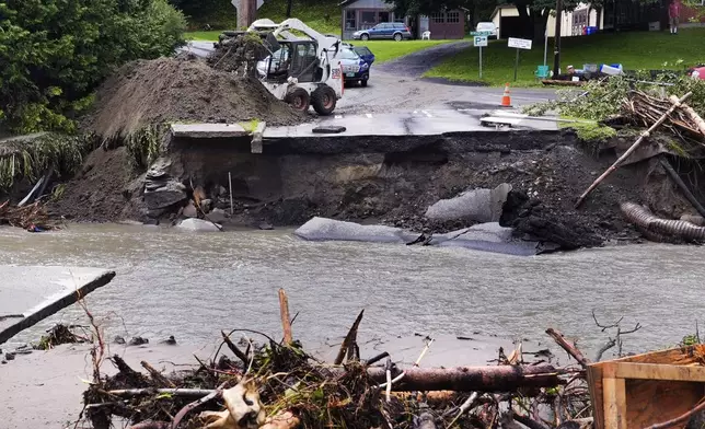 A loader dumps dirt along a washed out portion of Mill Street after remnants of Hurricane Beryl caused flooding and destruction, Friday, July 12, 2024, in Plainfield, Vt. (AP Photo/Charles Krupa)