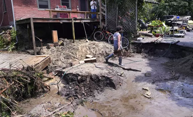 August Thompson walks over the washed out remains of the road in front of his grandfather's home after remnants of Hurricane Beryl caused flooding and destruction, Friday, July 12, 2024, in Plainfield, Vt. (AP Photo/Charles Krupa)