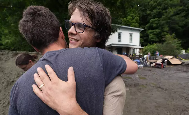 Homeowner Walker Blackwell, right, embraces his friend, Eli Yoder, who just flew out from Colorado to help in the clean up effort, after remnants of Hurricane Beryl caused flooding and destruction, Friday, July 12, 2024, in Plainfield, Vt. (AP Photo/Charles Krupa)