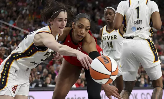 Indiana Fever guard Caitlin Clark, left, and Las Vegas Aces center A'ja Wilson, center, vie for a loose ball during the first half of a WNBA basketball game Tuesday, July 2, 2024, in Las Vegas. (Ellen Schmidt/Las Vegas Review-Journal via AP)