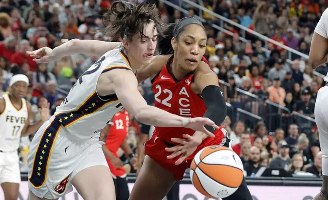 Indiana Fever guard Caitlin Clark (22) and Las Vegas Aces center A'ja Wilson (22) chase after a rebound during the first half of an WNBA basketball game Tuesday, July 2, 2024, in Las Vegas. (Steve Marcus/Las Vegas Sun via AP)