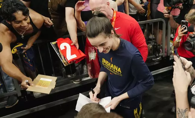 Indiana Fever guard Caitlin Clark, center, gives an autograph prior to a WNBA basketball game against the Phoenix Mercury, Sunday, June 30, 2024, in Phoenix. (AP Photo/Ross D. Franklin)