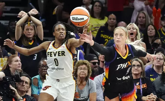 Indiana Fever guard Kelsey Mitchell (0) and Phoenix Mercury guard Sophie Cunningham (9) battle for a loose ball during the second half of a WNBA basketball game, Sunday, June 30, 2024, in Phoenix. (AP Photo/Ross D. Franklin)