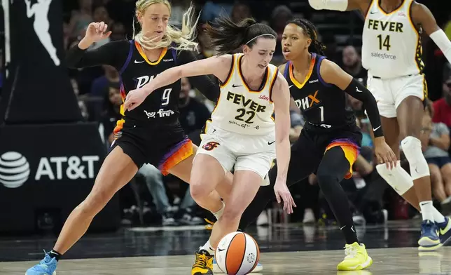 Indiana Fever guard Caitlin Clark (22) is defended by Phoenix Mercury guards Sophie Cunningham (9) and Sug Sutton (1) during the second half of a WNBA basketball game Sunday, June 30, 2024, in Phoenix. (AP Photo/Ross D. Franklin)
