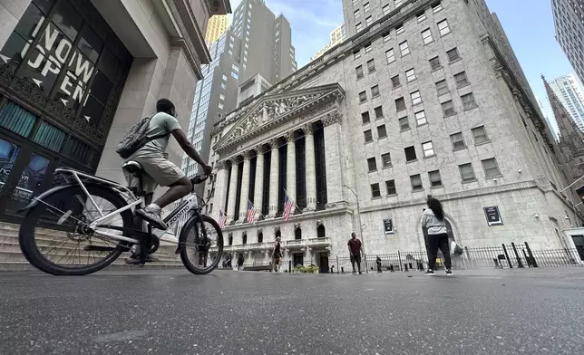 A bike rider approaches the New York Stock Exchange, rear, on Tuesday, July 9, 2024, in New York. Global shares are mostly higher, with Japan's benchmark Nikkei 225 jumping 2% to finish at another record high. (AP Photo/Peter Morgan)