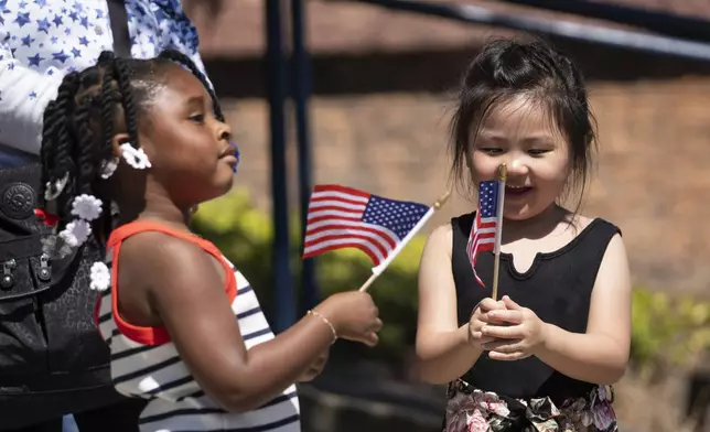 Elizabeth Weiter, 5, right, looks at a American flag as Camree Lee, 3, looks towards the parade during the annual Fourth of July Parade in Alameda, Calif. on Thursday, July 4, 2024. (Minh Connors/San Francisco Chronicle via AP)