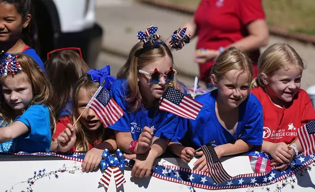 Eight-year-old Molly Perkins, third from left, joins fellow American Heritage Girls members in riding on a float during the Colorado 4th at Firestone parade to mark the Independence Day holiday Thursday, July 4, 2024, in Firestone, Colo. Floats, marching bands, classic cars and motorcycles were features in the annual parade through the Weld County community north of Denver. (AP Photo/David Zalubowski)