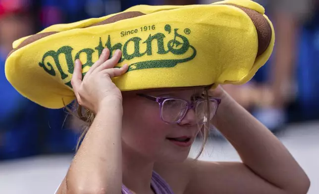 A girl holds her hot dog hat at the Nathan's Famous Fourth of July hot dog eating contest, Thursday, July 4, 2024, at Coney Island in the Brooklyn borough of New York. (AP Photo/Julia Nikhinson)