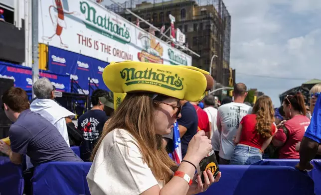 A woman wears a Nathan's hot dog hat at Nathan's Famous Fourth of July hot dog eating contest Thursday, July 4, 2024 at Coney Island in the Brooklyn borough of New York. (AP Photo/Julia Nikhinson)