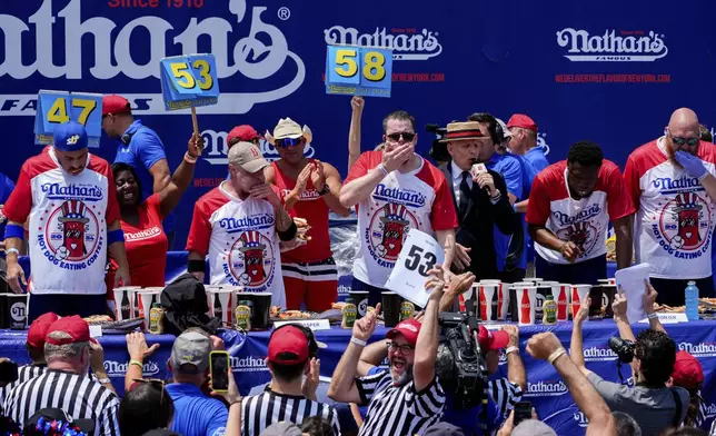 Patrick Bertoletti, center, competes in the men's division in Nathan's Famous Fourth of July hot dog eating contest, Thursday, July 4, 2024, at Coney Island in the Brooklyn borough of New York. Bertoletti ate 58 hot dogs. (AP Photo/Julia Nikhinson)