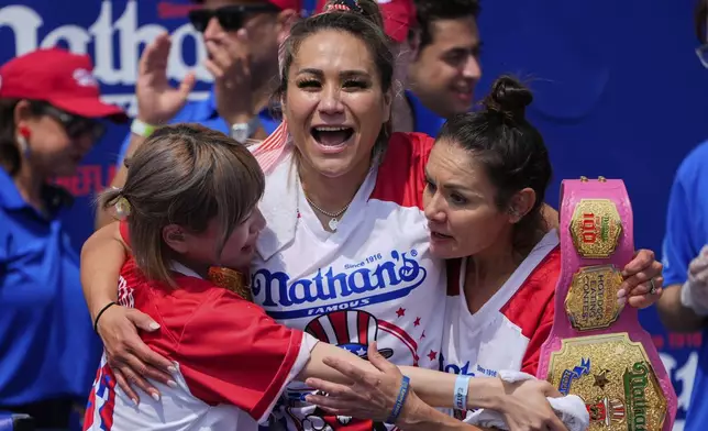 Miki Sudo, center, hugs Mayoi Ebihara, left, and Michelle Lesco, right, after winning the women's division of the Nathan's Famous Fourth of July hot dog eating contest, Thursday, July 4, 2024, at Coney Island in the Brooklyn borough of New York. Sudo ate a record 51 hot dogs. (AP Photo/Julia Nikhinson)