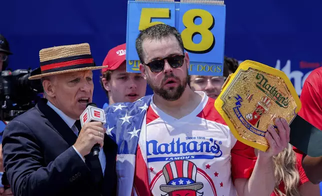 Patrick Bertoletti, right, reacts after winning the men's division in Nathan's Famous Fourth of July hot dog eating contest, Thursday, July 4, 2024, at Coney Island in the Brooklyn borough of New York. Bertoletti ate 58 hot dogs. (AP Photo/Julia Nikhinson)