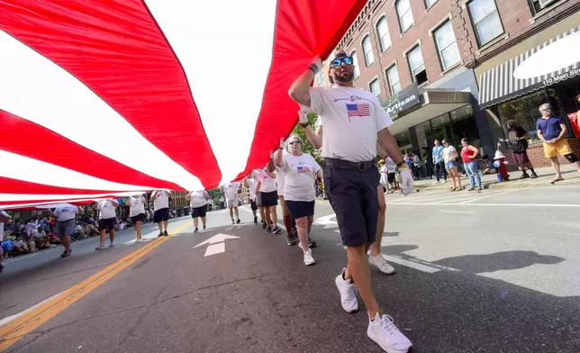 Chad Pacheco helps carry a large American flag down Main Street during the annual Brattleboro, Vt., Fourth of July parade on Thursday, July, 4, 2024. (Kristopher Radder/The Brattleboro Reformer via AP)