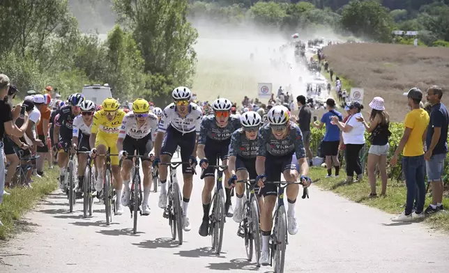 The pack with Denmark's Jonas Vingegaard, in second position, and Slovenia's Tadej Pogacar, wearing the overall leader's yellow jersey, rides on a gravel road during the ninth stage of the Tour de France cycling race over 199 kilometers (123.7 miles) with start and finish in Troyes, France, Sunday, July 7, 2024. (Bernard Papon/Pool Photo via AP)