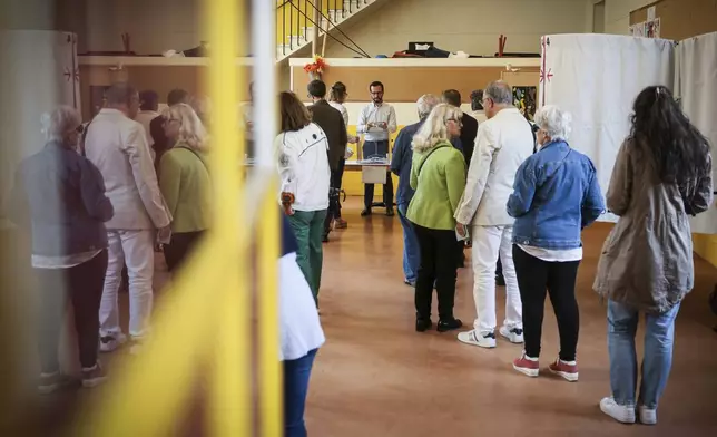 Voters waits to vote for the second round of the legislative elections, Sunday, July 7, 2024 in Paris. Voting has begun in mainland France on Sunday in pivotal runoff elections that could hand a historic victory to Marine Le Pen's far-right National Rally and its inward-looking, anti-immigrant vision — or produce a hung parliament and years of political deadlock. (AP Photo/Thomas Padilla)