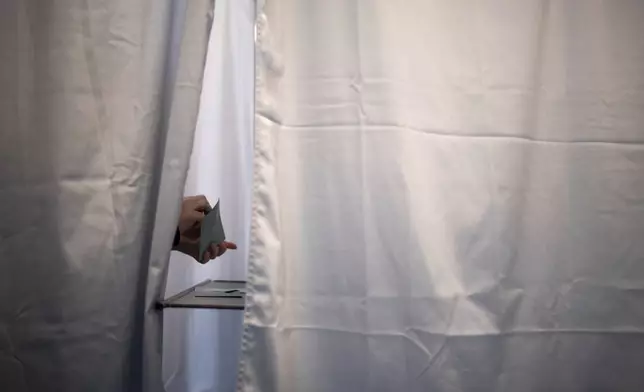 A voter places his ballot in the envelope during the second round of the legislative elections, Sunday, July 7, 2024 in Paris. France votes Sunday in pivotal runoff elections that could hand a historic victory to Marine Le Pen's far-right National Rally and its inward-looking, anti-immigrant vision — or produce a hung parliament and years of political deadlock. (AP Photo/Louise Delmotte)