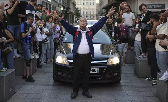 A man walks down the street as people react to projected results after the second round of the legislative elections, in Lyon, central France, Sunday, July 7, 2024. Polls have closed in France, and polling projections say a coalition on the left that came together unexpectedly has won the most parliamentary seats in the pivotal runoff elections after a high turnout among voters. (AP Photo/Laurent Cipriani)