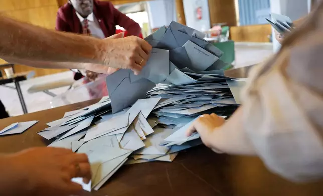 Polling station workers begin counting ballots during the second round of the legislative elections, Sunday, July 7, 2024 in Schiltgheim, eastern France. Voting is underway in mainland France on Sunday in pivotal runoff elections that could hand a historic victory to Marine Le Pen's far-right National Rally and its inward-looking, anti-immigrant vision, or produce a hung parliament and political deadlock. (AP Photo/Jean-Francois Badias)