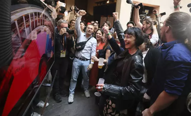 Supporters of the far-left La France Insoumise - LFI - (France Unbowed) parry react at the party election night headquarters, Sunday, July 7, 2024 in Paris. A coalition on the left that came together unexpectedly ahead of France's snap elections won the most parliamentary seats in the vote, according to polling projections Sunday. The surprise projections put President Emmanuel Macron's centrist alliance in second and the far right in third. At left is LFI's Mathilde Pant and at center Manuel Bompard. (AP Photo/Thomas Padilla)