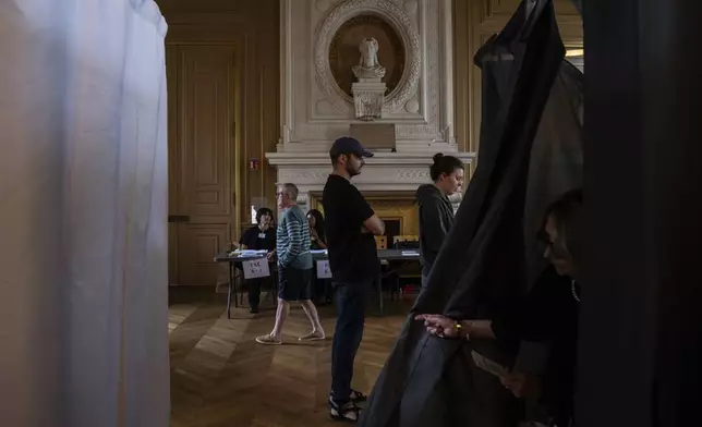 Voters line up to cast their vote during the second round of the legislative elections, Sunday, July 7, 2024 in Paris. France votes Sunday in pivotal runoff elections that could hand a historic victory to Marine Le Pen's far-right National Rally and its inward-looking, anti-immigrant vision — or produce a hung parliament and years of political deadlock. (AP Photo/Louise Delmotte)