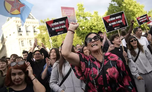 People react to the projection of results during the second round of the legislative elections, near Republique Plaza in Paris, France. Polls have closed in France, and polling projections say a coalition on the left that came together unexpectedly has won the most parliamentary seats in the pivotal runoff elections after a high turnout among voters. Sign reads "The extreme right shall not pass. From Gaza to Paris Intifada". (AP Photo/Christophe Ena)