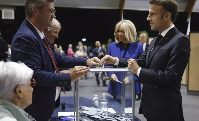 French President Emmanuel Macron, right, votes for the second round of the legislative elections in Le Touquet-Paris-Plage, northern France, Sunday July 7 2024. Voting has begun in mainland France on Sunday in pivotal runoff elections that could hand a historic victory to Marine Le Pen's far-right National Rally and its inward-looking, anti-immigrant vision — or produce a hung parliament and political deadlock. (Mohammed Badra, Pool via AP)