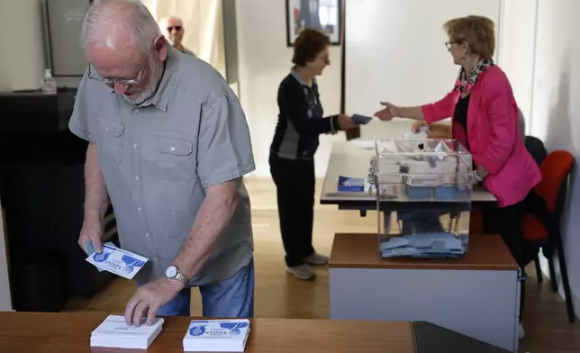 A man picks up ballots in a the voting station during the second round of the legislative elections, Sunday, July 7, 2024 in Olwisheim , eastern France. France votes Sunday in pivotal runoff elections that could hand a historic victory to Marine Le Pen's far-right National Rally and its inward-looking, anti-immigrant vision — or produce a hung parliament and years of political deadlock. (AP Photo/Jean-Francois Badias)