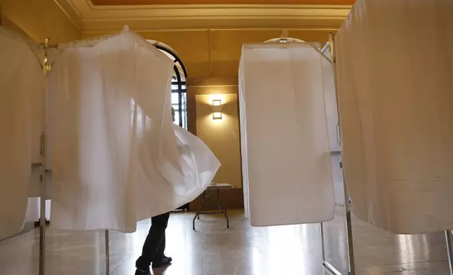 A voter leaves the voting booth before voting in the second round of the legislative elections, Sunday, July 7, 2024 in Strasbourg, eastern France. France votes Sunday in pivotal runoff elections that could hand a historic victory to Marine Le Pen's far-right National Rally and its inward-looking, anti-immigrant vision — or produce a hung parliament and years of political deadlock. (AP Photo/Jean-Francois Badias)