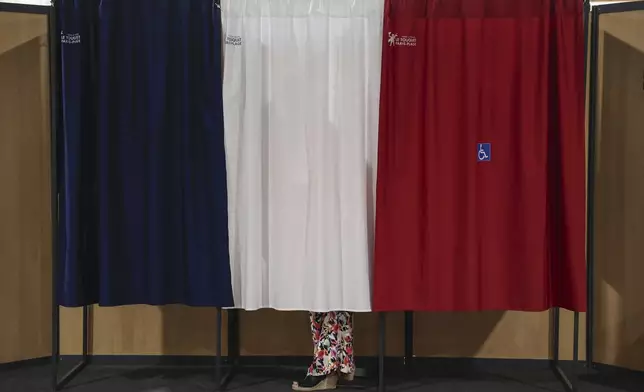 A voter stands in the polling booth during the second round of the legislative elections in Le Touquet-Paris-Plage, northern France, Sunday July 7 2024. Voting has begun in mainland France on Sunday in pivotal runoff elections that could hand a historic victory to Marine Le Pen's far-right National Rally and its inward-looking, anti-immigrant vision — or produce a hung parliament and political deadlock. (Mohammed Badra, Pool via AP)