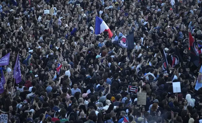 People stand in Republique Plaza as they react to the projection of results during the second round of the legislative elections, in Paris, France. Polls have closed in France, and polling projections say a coalition on the left that came together unexpectedly has won the most parliamentary seats in the pivotal runoff elections after a high turnout among voters. (AP Photo/Christophe Ena)