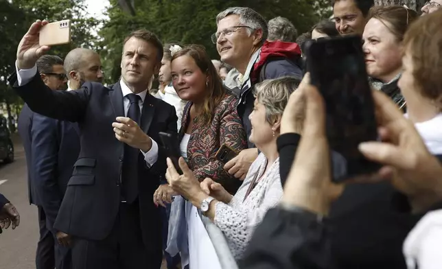 French President Emmanuel Macron makes a selfie for supporters after voting for the second round of the legislative elections in Le Touquet-Paris-Plage, northern France, Sunday July 7 2024. Voting has begun in mainland France on Sunday in pivotal runoff elections that could hand a historic victory to Marine Le Pen's far-right National Rally and its inward-looking, anti-immigrant vision — or produce a hung parliament and political deadlock. (Mohammed Badra, Pool via AP)