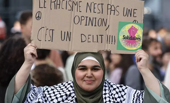 A woman holds a sign which reads in French '"Racism is not an opinion, it is a crime" as she waits for the results of the second round of the legislative elections, Sunday, July 7, 2024 in Nantes, western France. Voting is underway in mainland France on Sunday in pivotal runoff elections that could hand a historic victory to Marine Le Pen's far-right National Rally and its inward-looking, anti-immigrant vision, or produce a hung parliament and political deadlock. (AP Photo/Jeremias Gonzalez)