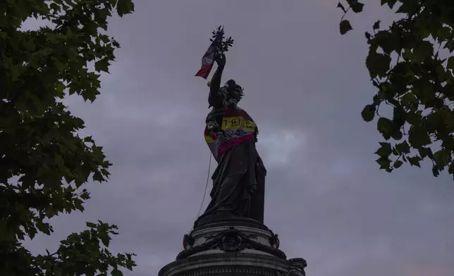 Statue of Republique plaza is decorated by flags as people gather there in a protest against the far-right, Wednesday, July 3, 2024, in Paris. French opposition parties and associations are trying to block a landslide victory for Marine Le Pen's far-right National Rally in next Sunday's second round of legislative elections. (AP Photo/Louise Delmotte)