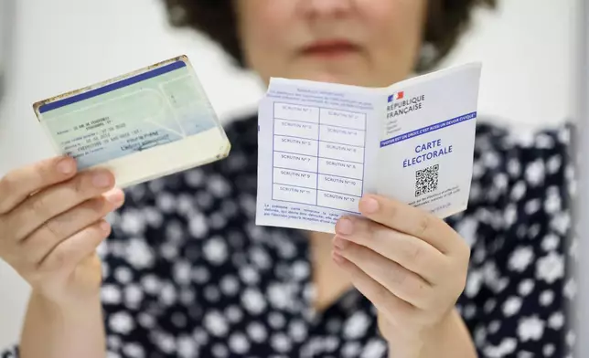 A voting assistant checks the voting card, right, and an identity card in Strasbourg, eastern France, Sunday, June 30, 2024. (AP Photo/Jean-Francois Badias)