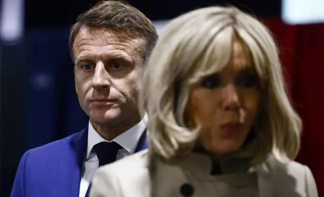 French President Emmanuel Macron and his wife Brigitte Macron stand in the voting station before voting in Le Touquet-Paris-Plage, northern France, Sunday, June 30, 2024. (Yara Nardi, Pool via AP)