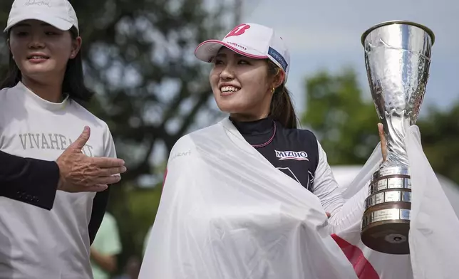 Ayaka Furue, of Japan, celebrates with her trophy after winning the Evian Championship women's golf tournament, in Evian, eastern France, Sunday, July 14, 2024. (AP Photo/Laurent Cipriani)