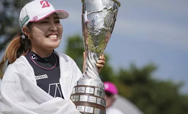 Ayaka Furue, of Japan, celebrates with her trophy after winning the Evian Championship women's golf tournament, in Evian, eastern France, Sunday, July 14, 2024. (AP Photo/Laurent Cipriani)