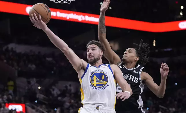 FILE - Golden State Warriors guard Klay Thompson (11) scores past San Antonio Spurs guard Devin Vassell, right, during the second half of an NBA basketball game in San Antonio, Monday, March 11, 2024. Klay Thompson is moving on from the Golden State Warriors, with the four-time league champion agreeing to join the Western Conference champion Dallas Mavericks and change franchises for the first time in his 13-year NBA career, two people with knowledge of the decision said Monday, July 1, 2024.(AP Photo/Eric Gay, File)