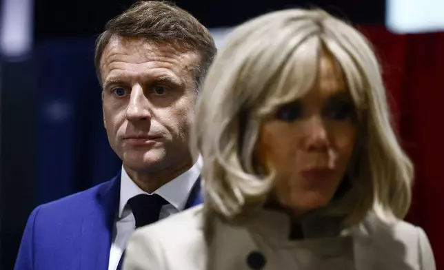FILE - French President Emmanuel Macron and his wife Brigitte Macron stand in the voting station before voting in Le Touquet-Paris-Plage, northern France, Sunday, June 30, 2024. After France’s far-right National Rally surged into the lead in the first round of legislative elections, some European neighbors are warily eyeing the latest country on the continent to veer to the right. (Yara Nardi, Pool via AP, File)